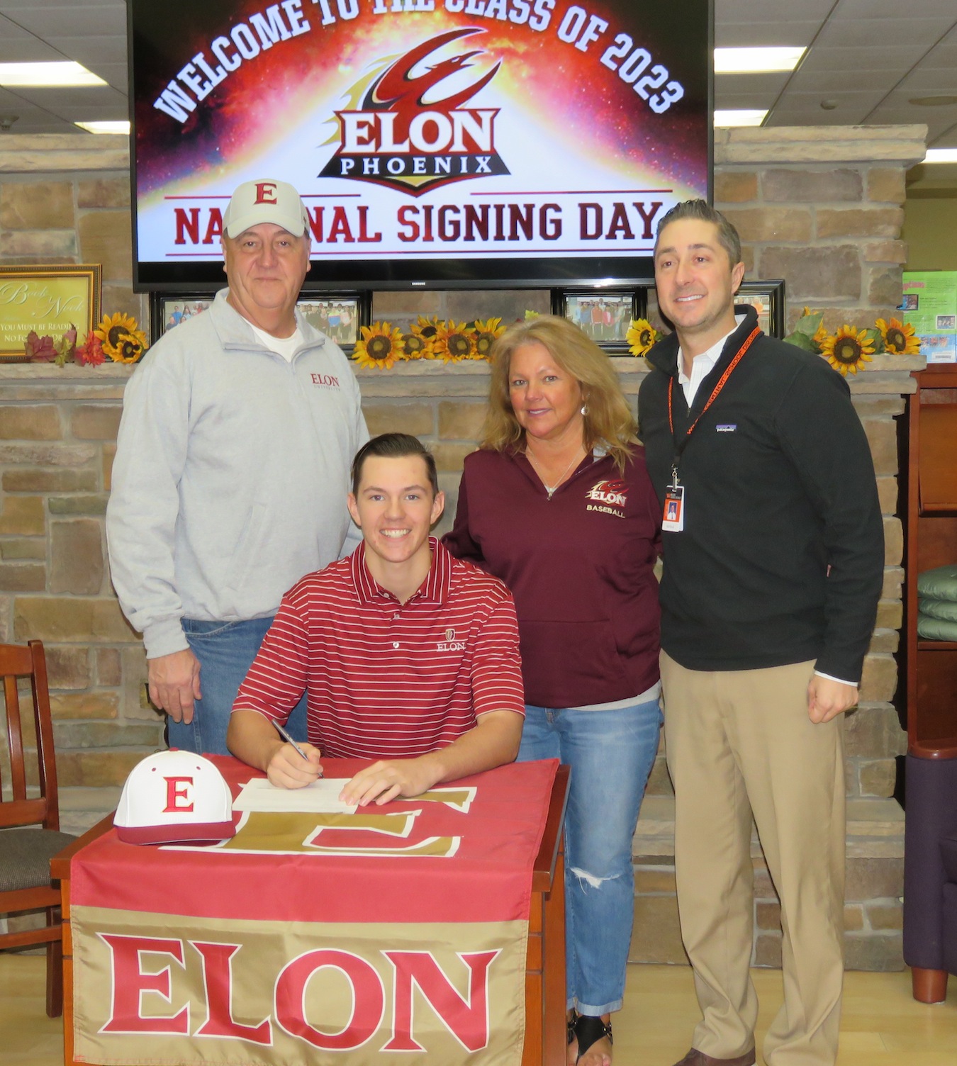 Ian Evans, sitting, signs his national letter of intent to play baseball at Elon University. Flanking Evans, from left, Lyle Evans, Diane Maggliazo and Wilson Athletic Director Jeff Roth. (Photos by David Yarger)